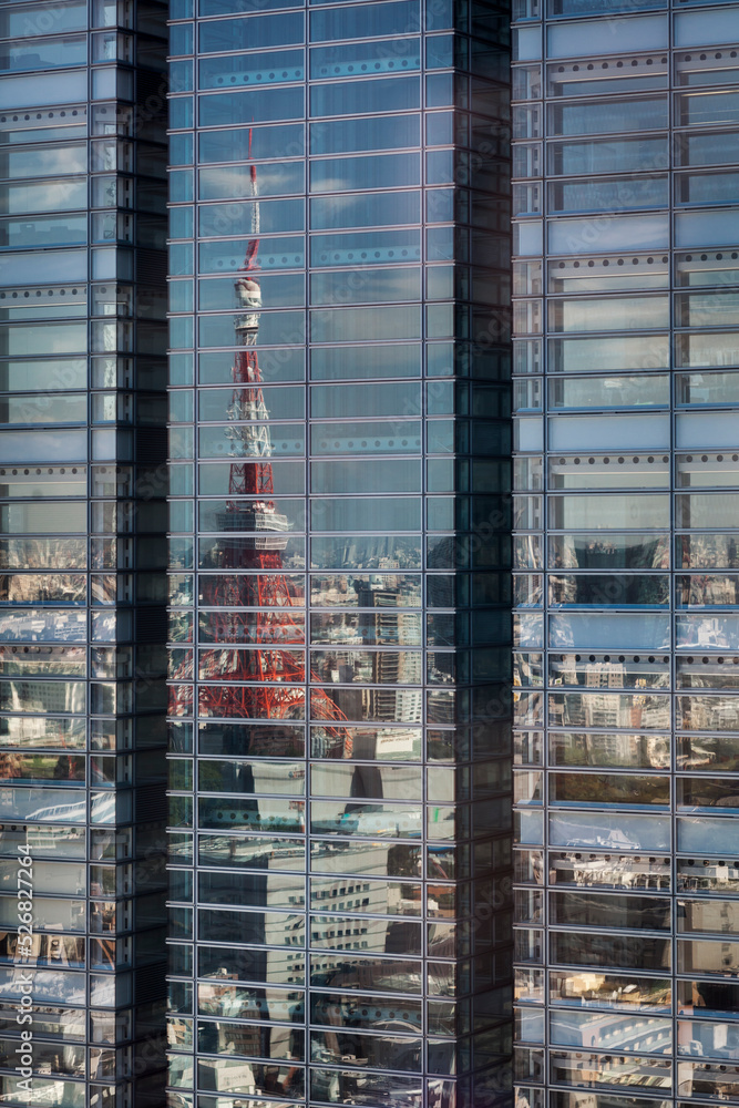 Distorted Tokyo Tower reflection on a glass skyscraper in Minato City