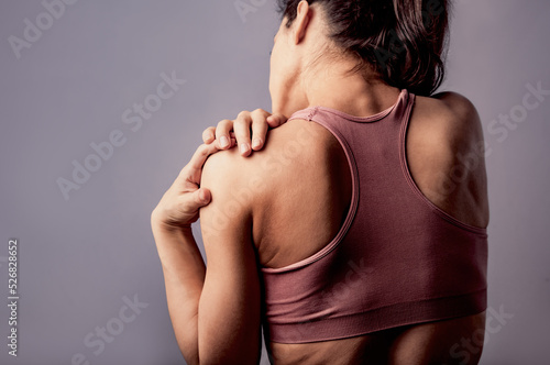 Young strong sporty woman doing the hands the massege to relax the tension shoulder and blades in sport wear. Sports exercising injury. Closeup portrait. Back view. The concept of medicine