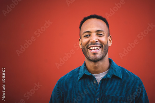 Handsome man laughing over maroon bacckground