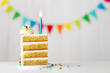 Slice of birthday cake with blue candle and colorful birthday bunting