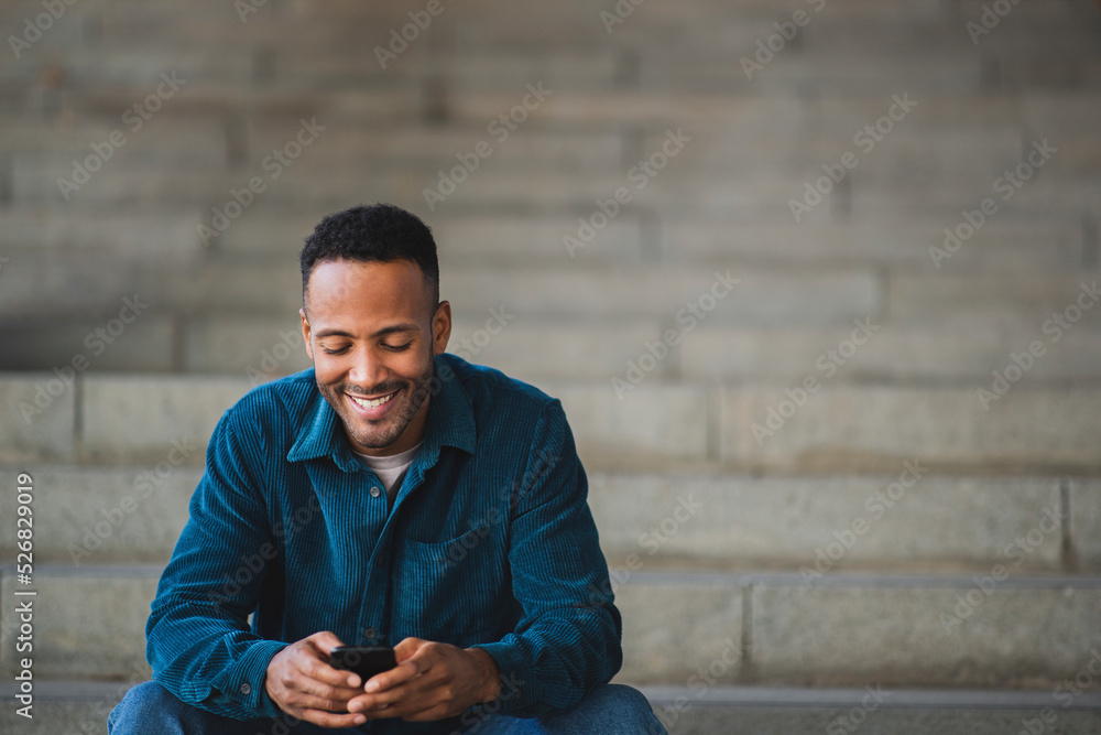 Obraz premium Smiling man text messaging using mobile phone
