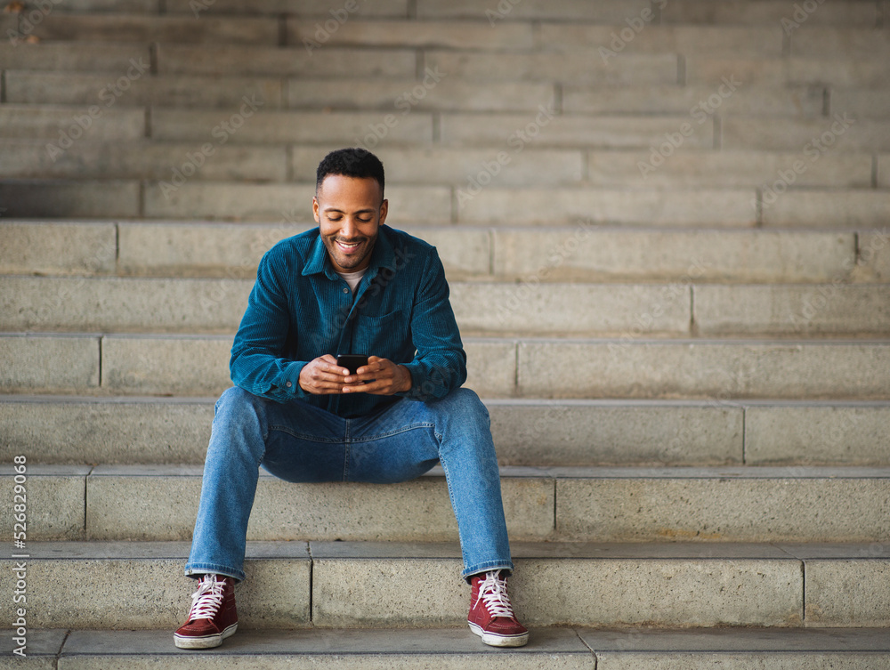 Man using smart phone while sitting on stairs Man using smart phone while sitting on stairs