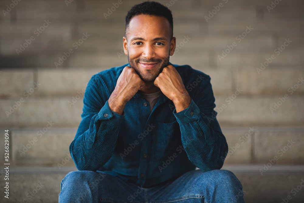 Happy man posing while sitting outdoors on steps