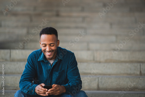 Smiling man text messaging using mobile phone