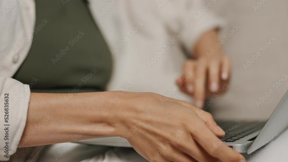 Woman typing on gray laptop on keyboard in close-up with laptop in her lap Woman typing on gray laptop on keyboard in close-up with laptop in her lap