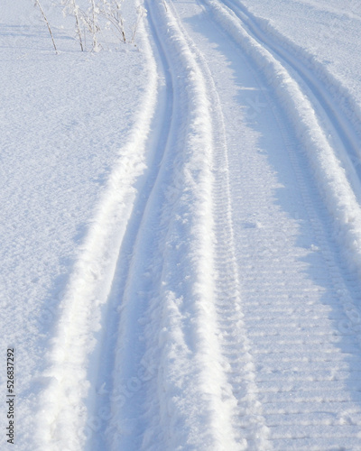 Track of traces from a snowmobile in drifts of white snow. Nature and outdoor. Winter theme. Vertical stories with snowy field © Deacon docs