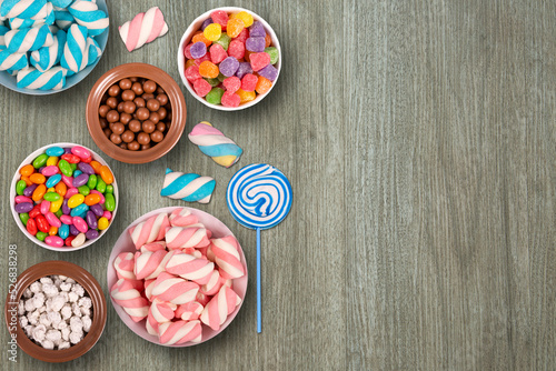 Colorful candies, marshmellows, chocolate balls in jars, lollipops and sweet peanuts and copy space