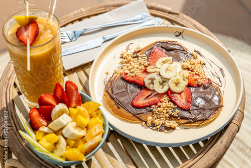 Fruit salad, smoothie and delicious pancakes with sweet strawberries, banana and chocolate 