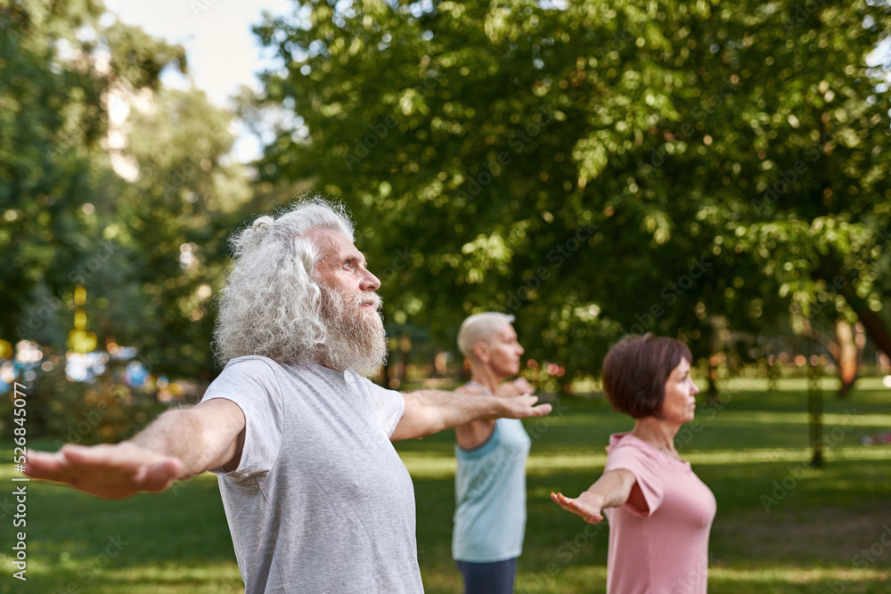 Fototapeta premium Concentrated man with blur friends practicing yoga