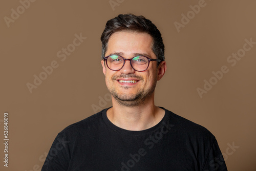 Stylish caucasian man in glasses and black shirt on brown background © Simonforstock