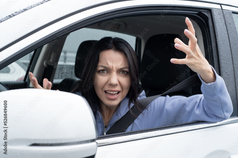 Portrait of a Shocked and aggressive talking young woman, driver inside a car. Concept Road trip Insurance accident.