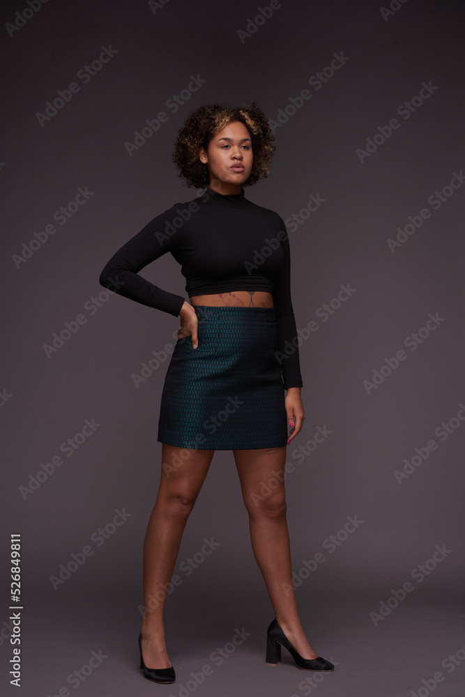 Young multi-ethnic woman in elegant casualwear standing against grey background and looking forwards during photo session Young multi-ethnic woman in elegant casualwear standing against grey background and looking forwards during photo session