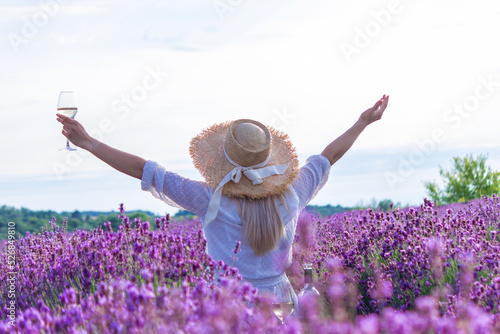 a girl in a lavender field pours wine into a glass. Relaxation.