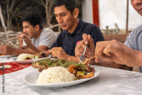Men eating in a table with dishes with rice and grilled guinea pig photo