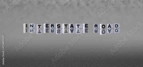 interstate road word or concept represented by black and white letter cubes on a grey horizon background stretching to infinity