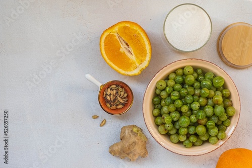 Prepared ingredients for making gooseberry jam on a light concrete background. Canning  harvest.
