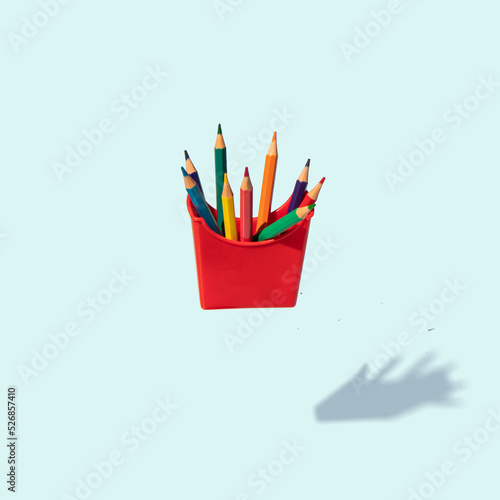 Minimal composition with colored pencils on pastel bright blue background. Back to school idea. Creative education concept. Fast food inspiration.