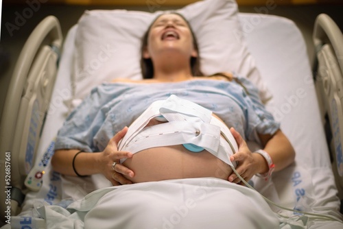 Картината върху платно A woman having painful contractions lying in the hospital bed waiting for labor