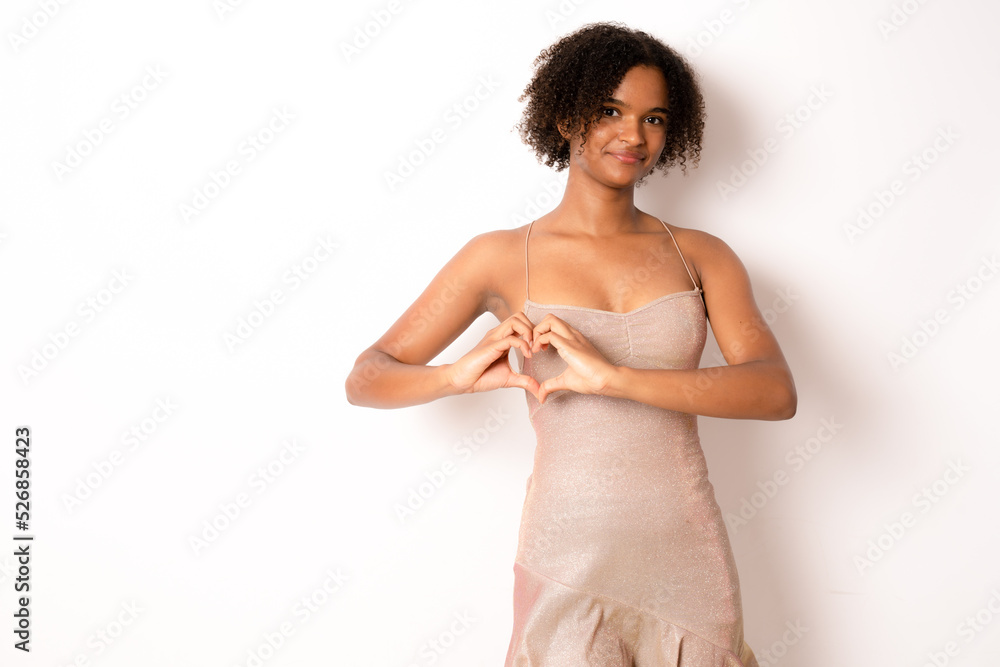 Pretty curly African American woman confesses in love, makes heart gesture, shows her true feelings, has happy expression, wears elegant party dress, poses over white background. Relationship concept Pretty curly African American woman confesses in love, makes heart gesture, shows her true feelings, has happy expression, wears elegant party dress, poses over white background. Relationship concept