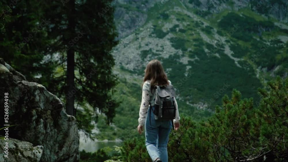 the girl walks with a backpack against the background of mountains and stones in slow motion the girl walks with a backpack against the background of mountains and stones in slow motion