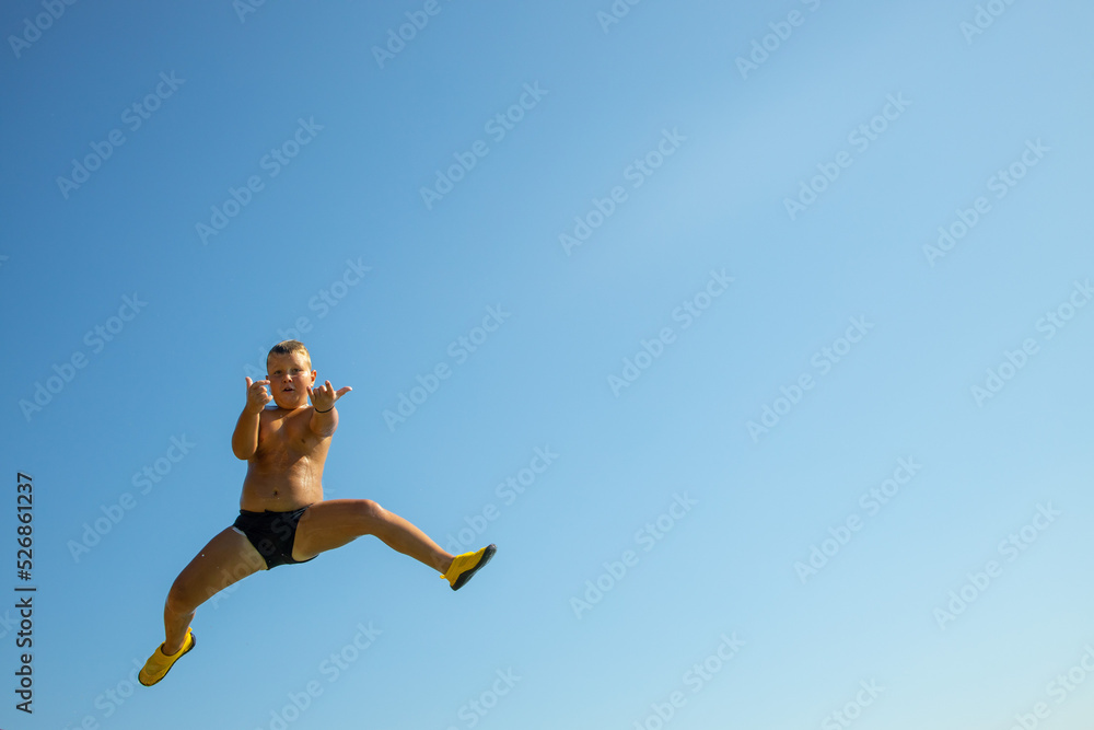Jump into the water. a boy caught jumping into the water. caught in the moment of flight Jump into the water. a boy caught jumping into the water. caught in the moment of flight