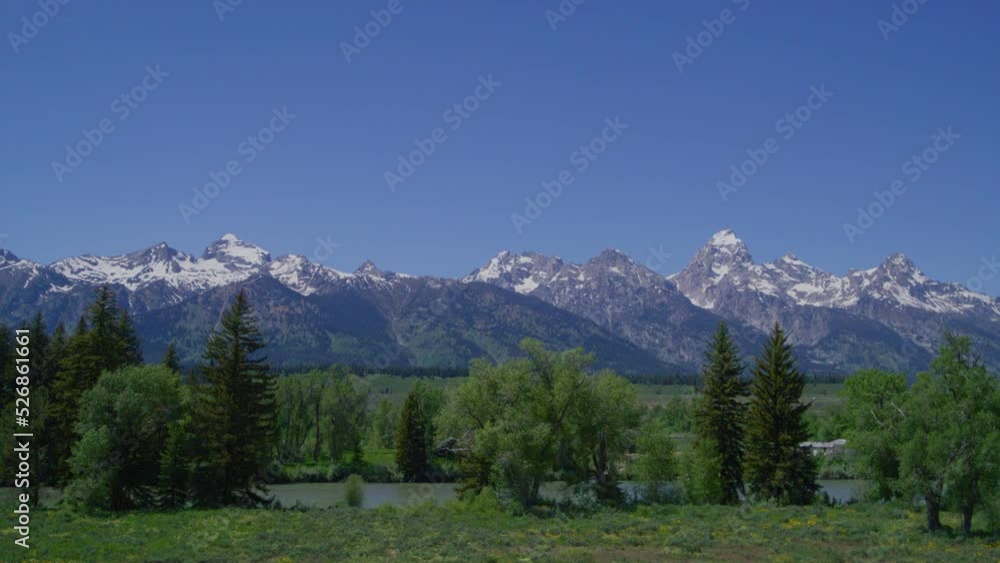 Teton Range with mountain ranges covered in snow. Beautiful sanctuary with lush green valleys, charming alpine lake and tall summits in National Park. High quality 4k footage Teton Range with mountain ranges covered in snow. Beautiful sanctuary with lush green valleys, charming alpine lake and tall summits in National Park. High quality 4k footage