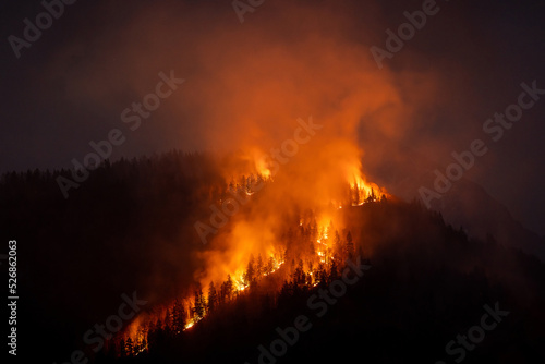 Smoke rises after a wildfire over a mountain area, threatening health and biodiversity, aerial view.