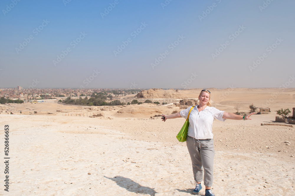 a plump young woman in light cotton clothes stands in the middle of a desert
