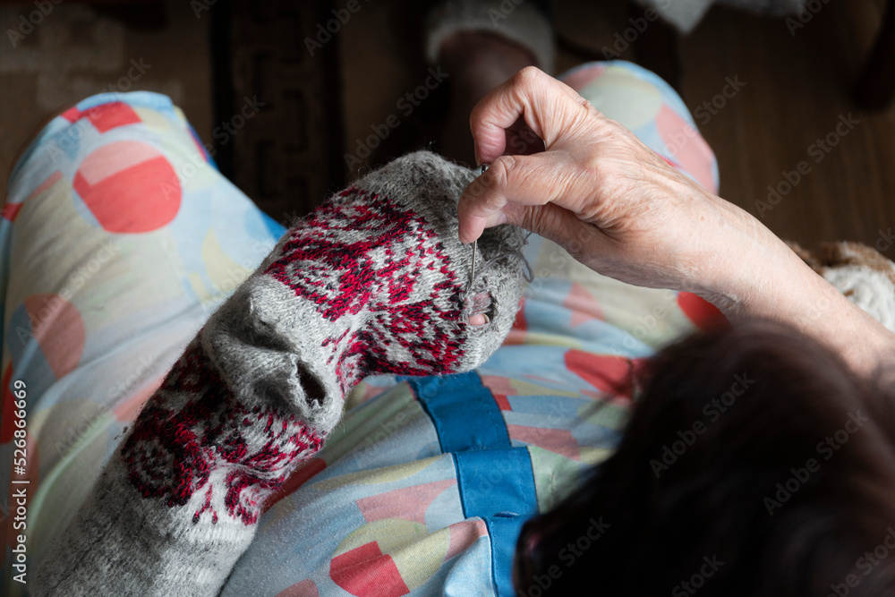 Close up of old lady hands darning winter socks with hole. Poverty in world economic crisis concept  - obrazy, fototapety, plakaty 