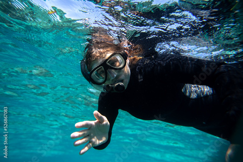 young woman in wet suit snorkling off the coast of Hopkins in Belize