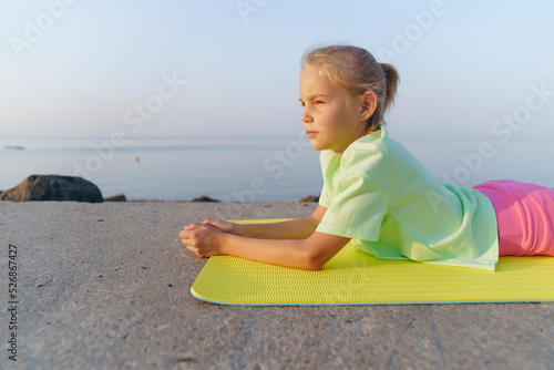 A girl on the beach doing yoga is lying on a yoga mat. photo