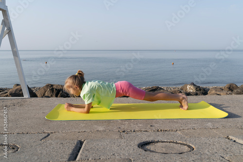 The girl doing yoga, stands in plank pose on the yoga mat. photo