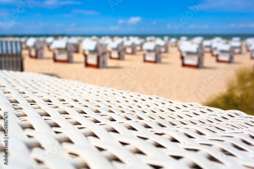 Holiday Relaxation Place at Coast / Detail braided white roof beach chair on foreground and defocused background of many more at summer beach