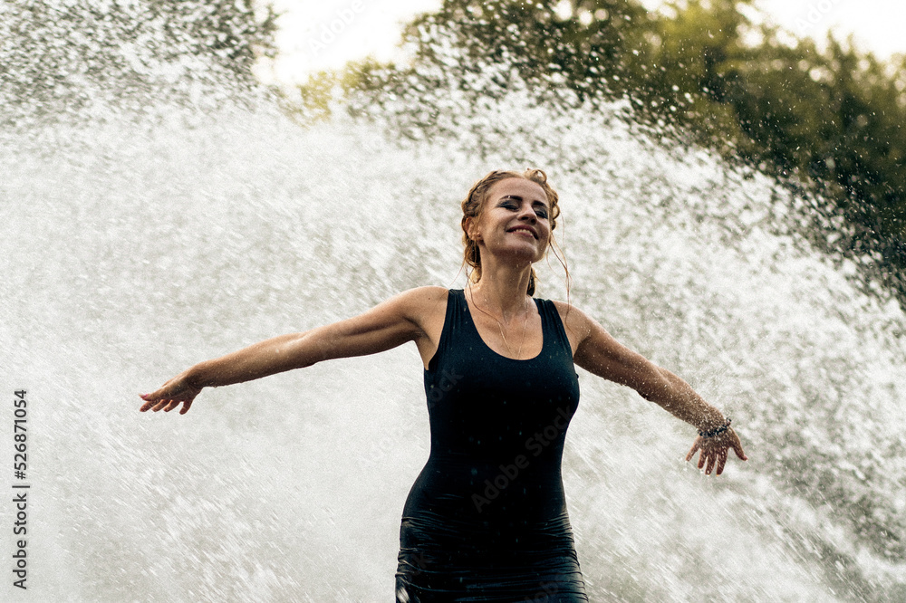 Fototapeta premium Happy woman having fun at the city fountain on a summer day.