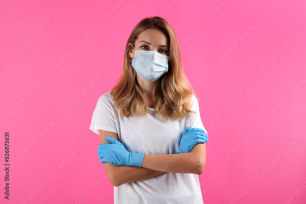 Young woman in medical gloves and protective mask on pink background Young woman in medical gloves and protective mask on pink background