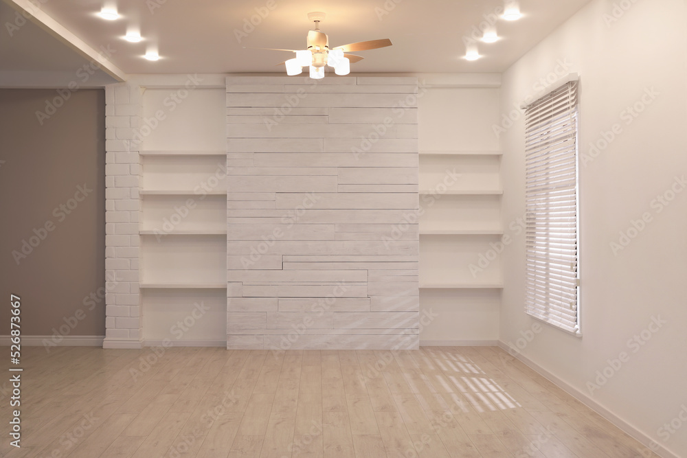 Fototapeta premium Empty room with textured wall, stylish wooden shelves and large window