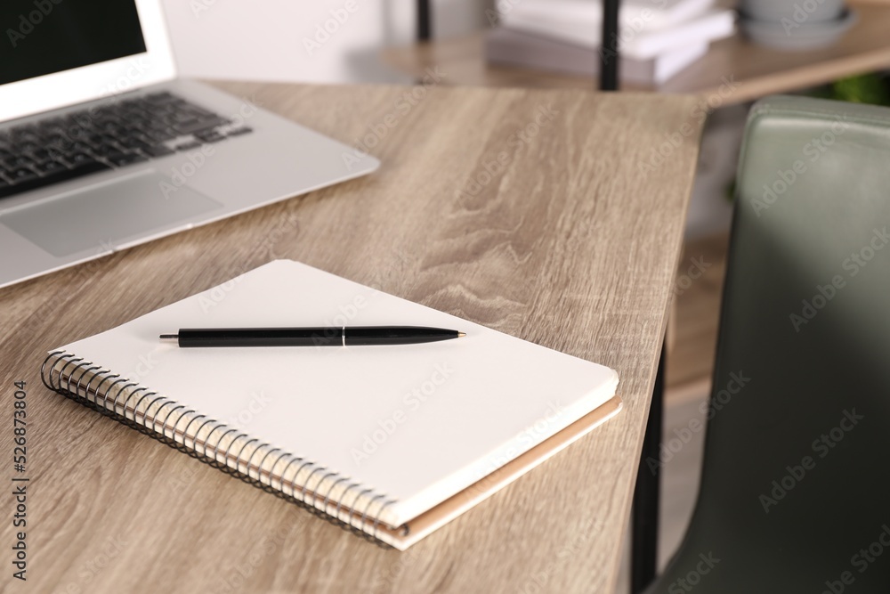 Notebook, pen and laptop on wooden table indoors Notebook, pen and laptop on wooden table indoors