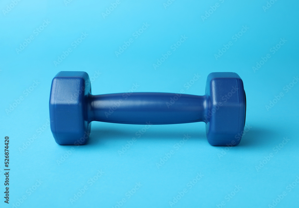 Stylish dumbbell on light blue background, closeup Stylish dumbbell on light blue background, closeup