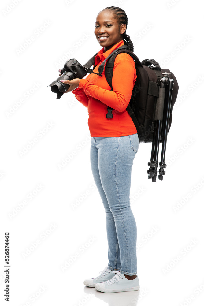 people, profession and photography concept - happy smiling woman photographer with digital camera, backpack and tripod over white background