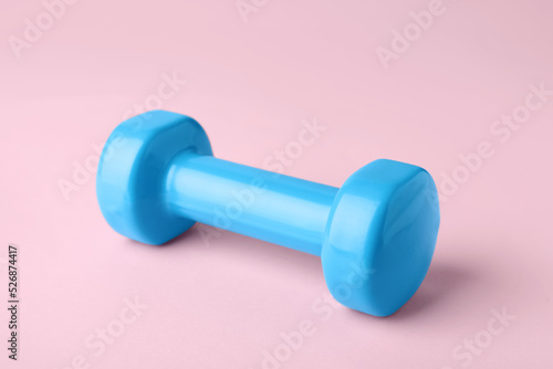 One turquoise dumbbell on light pink background