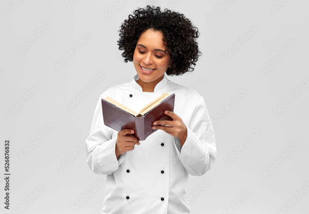 Fototapeta premium cooking, culinary and people concept - happy smiling female chef reading cook book over white background
