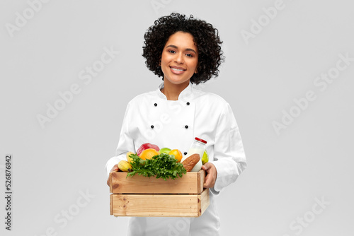 cooking  culinary and people concept - happy smiling female chef holding food in wooden box over grey background