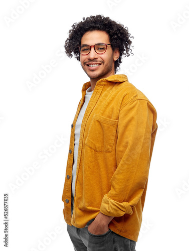 people and fashion concept - happy smiling man in glasses and yellow jacket with hands in pockets over white background