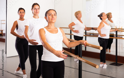 Latino woman in leotard training in ballet class with other dancers