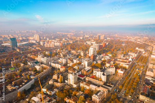 Aerial view camera flight above the autumn city in foggy weather with many buildings and roads and highways. Weather. Cloudy. Modern. Scenic. Vegetation. Autumn Forest. October. Leaf. Park. Landmark