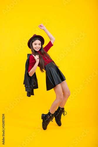 Full length funny teenager kid jump enjoy rejoice win isolated on yellow background. Small child girl in summer dress jumping. Fashion trendy kids look, child model in vogue fashionable style outfit.