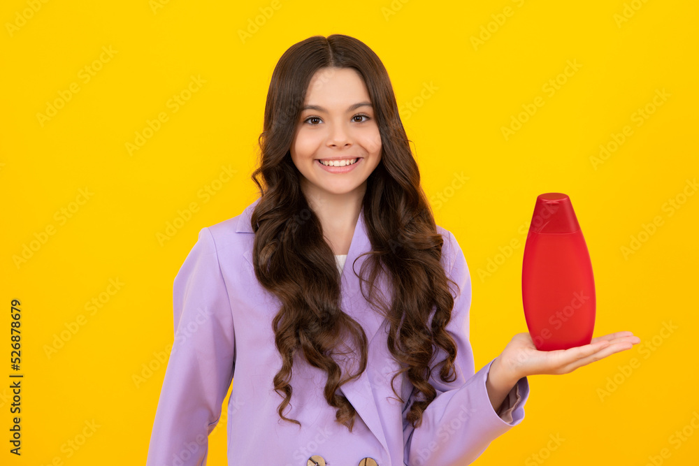 Teen child girl with shampoo bottle or shower gel isolated on yellow background. Kids hair cosmetic product. Happy teenager, positive and smiling emotions of teen girl. Teen child girl with shampoo bottle or shower gel isolated on yellow background. Kids hair cosmetic product. Happy teenager, positive and smiling emotions of teen girl.