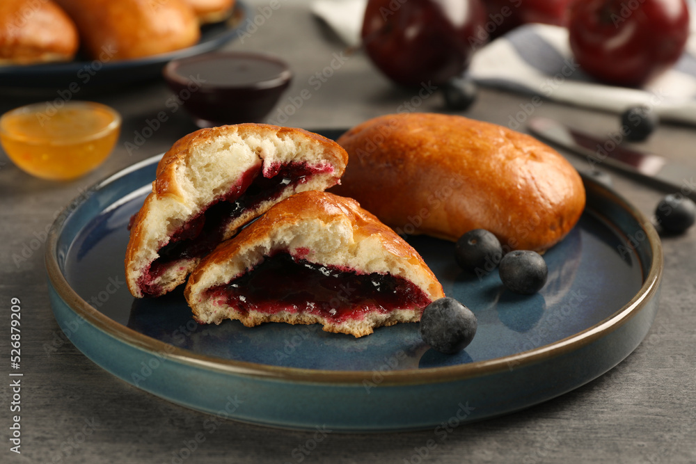 Delicious baked patties with jam and blueberries on grey table, closeup Delicious baked patties with jam and blueberries on grey table, closeup