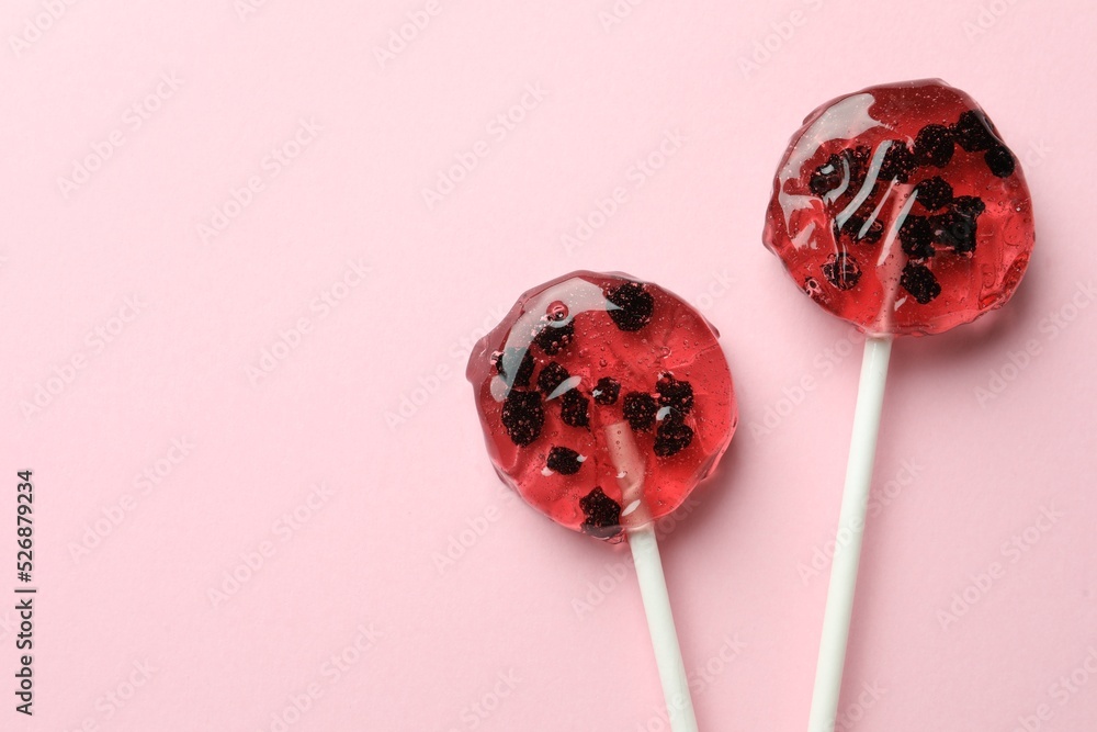 Sweet colorful lollipops with berries on pink background, flat lay. Space for text Sweet colorful lollipops with berries on pink background, flat lay. Space for text