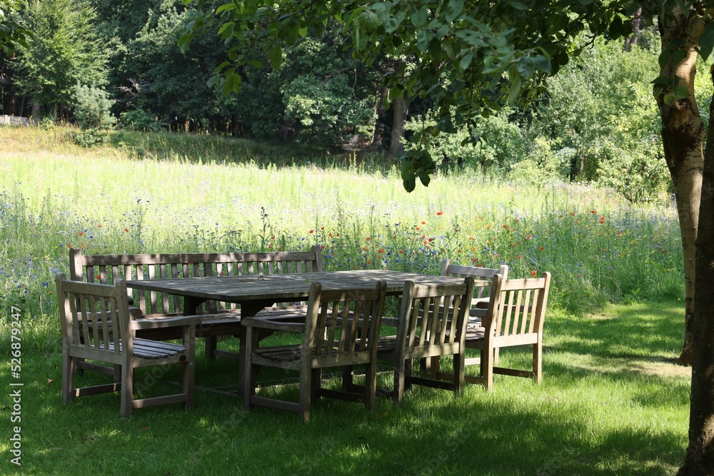 Empty wooden table with bench and chairs in garden Empty wooden table with bench and chairs in garden